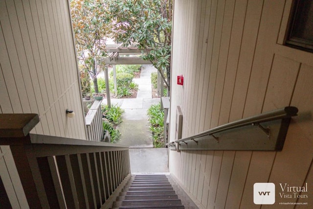 stairway featuring wooden walls