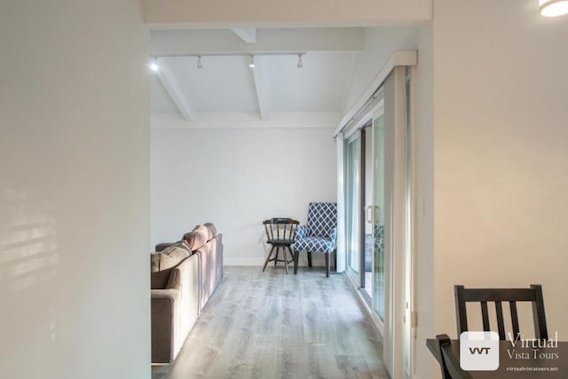 corridor featuring beam ceiling, light hardwood / wood-style floors, and rail lighting