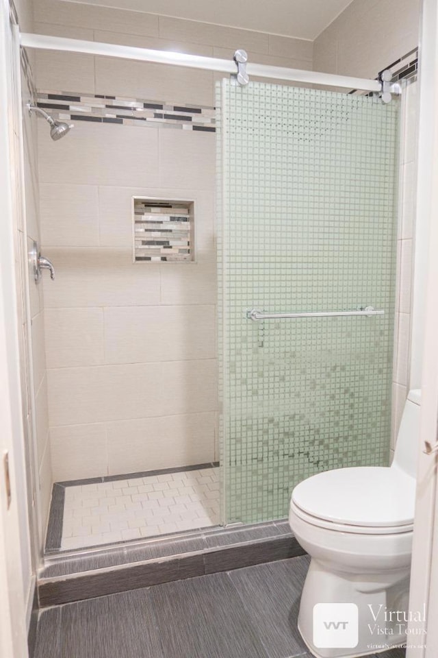 bathroom featuring toilet and a shower with shower door