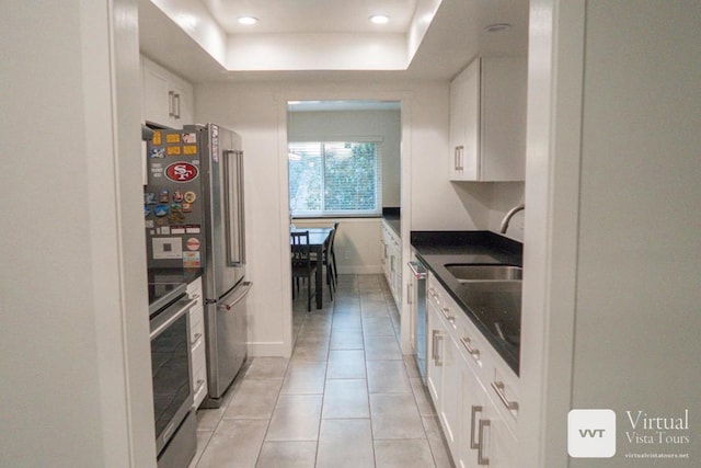 kitchen featuring appliances with stainless steel finishes, white cabinets, and a tray ceiling