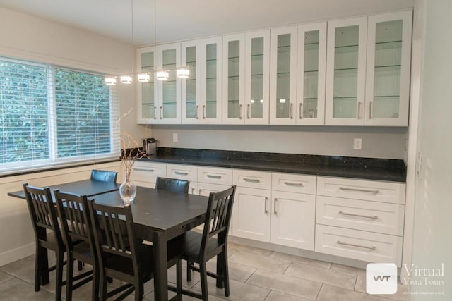 kitchen featuring decorative light fixtures, a breakfast bar, light tile patterned floors, and white cabinets