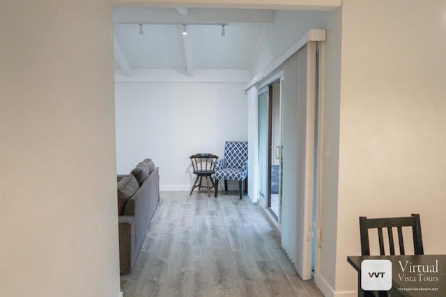 corridor featuring track lighting, lofted ceiling with beams, and light wood-type flooring