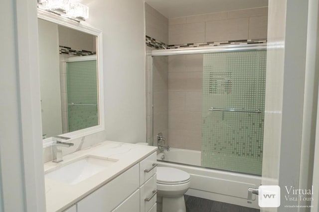 full bathroom featuring vanity, shower / bath combination with glass door, and toilet