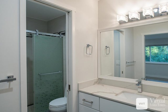 bathroom with vanity, a shower with shower door, and toilet