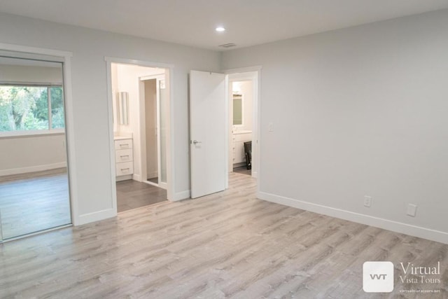 unfurnished bedroom featuring light wood-type flooring and ensuite bath