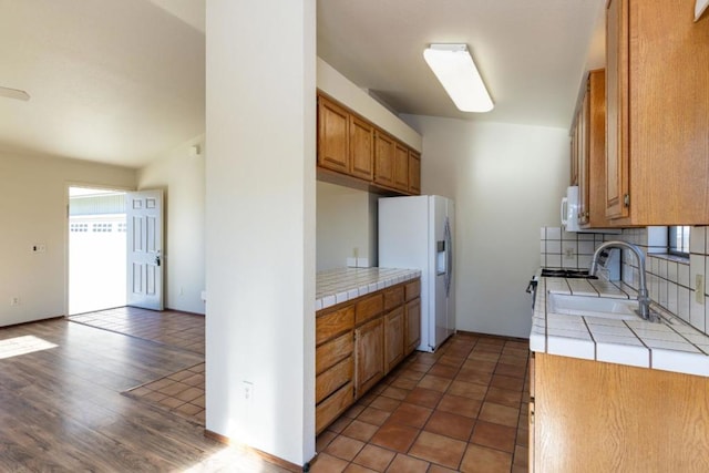 kitchen with sink, tasteful backsplash, tile countertops, dark tile patterned floors, and white appliances