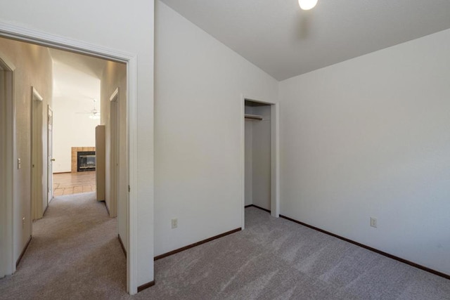 interior space with lofted ceiling, a tiled fireplace, light carpet, and a closet