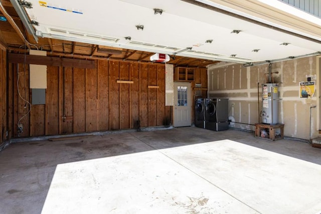 garage with independent washer and dryer, a garage door opener, wood walls, and gas water heater