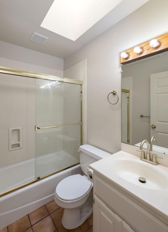 full bathroom with a skylight, enclosed tub / shower combo, vanity, toilet, and tile patterned floors