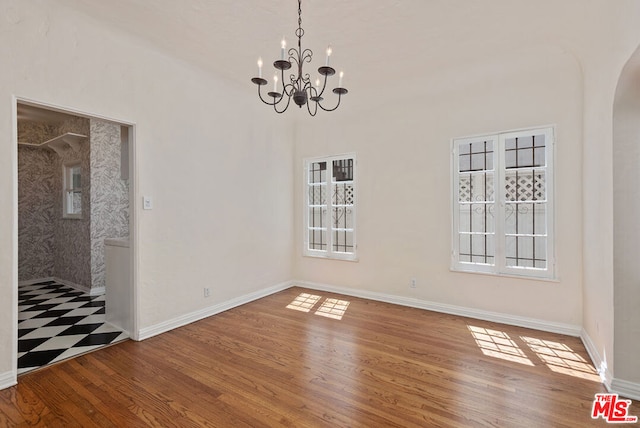 unfurnished dining area featuring hardwood / wood-style flooring and an inviting chandelier