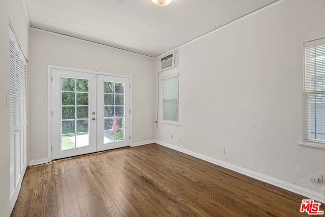 empty room with french doors, wood-type flooring, a wall mounted air conditioner, and plenty of natural light