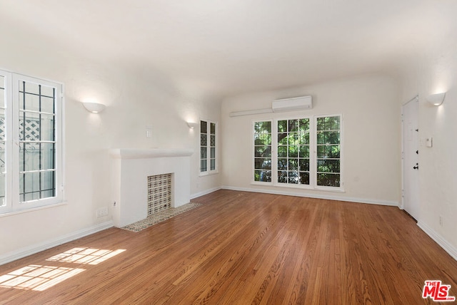 unfurnished living room with wood-type flooring and a wall unit AC