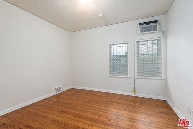 spare room featuring hardwood / wood-style flooring and a wall mounted AC