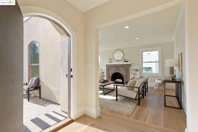 entrance foyer featuring crown molding, a fireplace, and light wood-type flooring