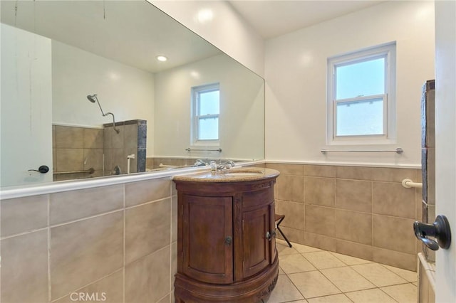 bathroom with tile patterned floors, vanity, tile walls, and a shower