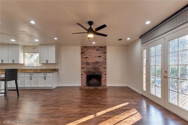 living room with a fireplace, dark wood-type flooring, french doors, and ceiling fan