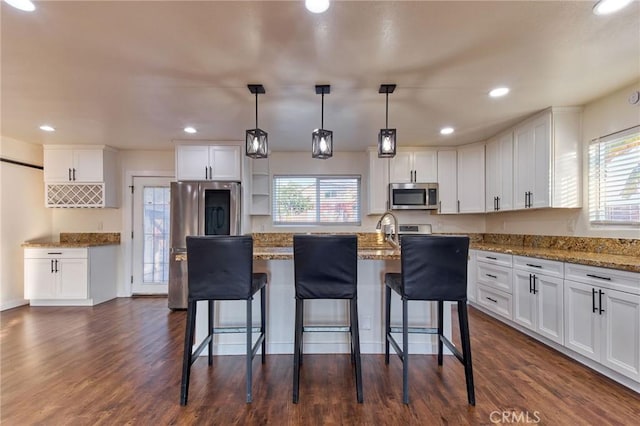 kitchen featuring stainless steel appliances, white cabinets, and decorative light fixtures