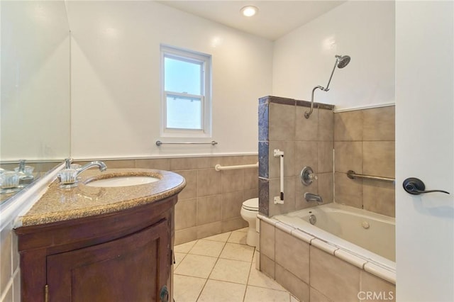 full bathroom featuring toilet, tile walls, vanity, tiled shower / bath combo, and tile patterned flooring