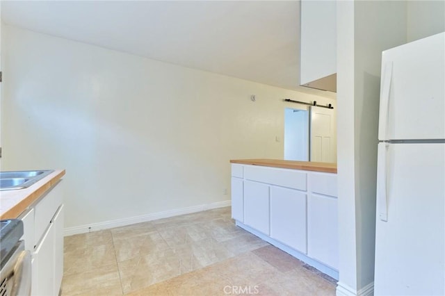 kitchen with stove, a barn door, white fridge, and white cabinets