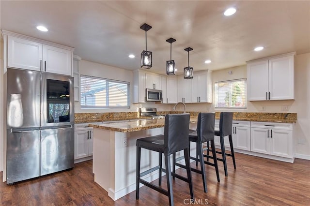 kitchen featuring hanging light fixtures, a kitchen island, white cabinets, and appliances with stainless steel finishes