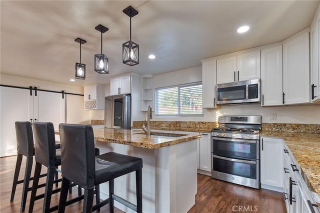 kitchen featuring appliances with stainless steel finishes, a breakfast bar, an island with sink, sink, and white cabinets