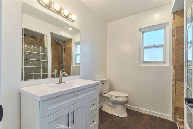 bathroom with vanity, wood-type flooring, toilet, and tiled shower