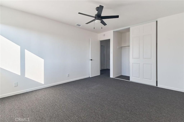 unfurnished bedroom with dark colored carpet, ceiling fan, and a closet