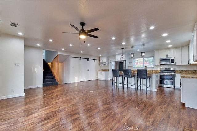 interior space with dark hardwood / wood-style floors, ceiling fan, and a barn door