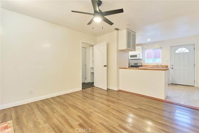 unfurnished living room featuring light hardwood / wood-style flooring and ceiling fan