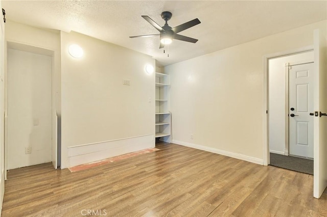 spare room with ceiling fan, a textured ceiling, and light wood-type flooring