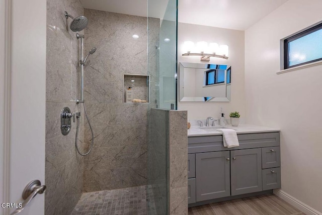 bathroom featuring vanity, wood-type flooring, and tiled shower