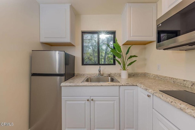 kitchen with sink, light stone countertops, white cabinets, and appliances with stainless steel finishes