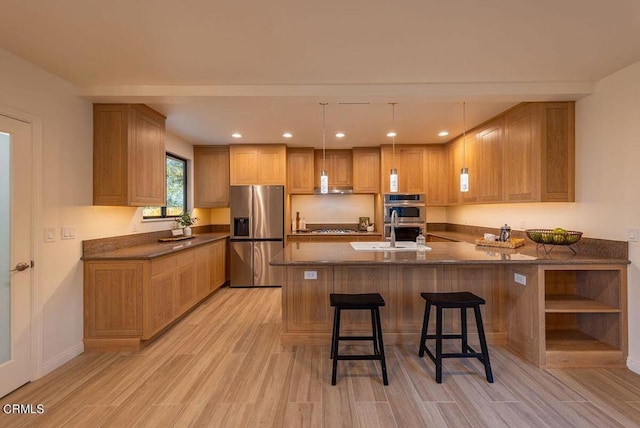 kitchen with stainless steel appliances, a kitchen bar, light wood-type flooring, and kitchen peninsula