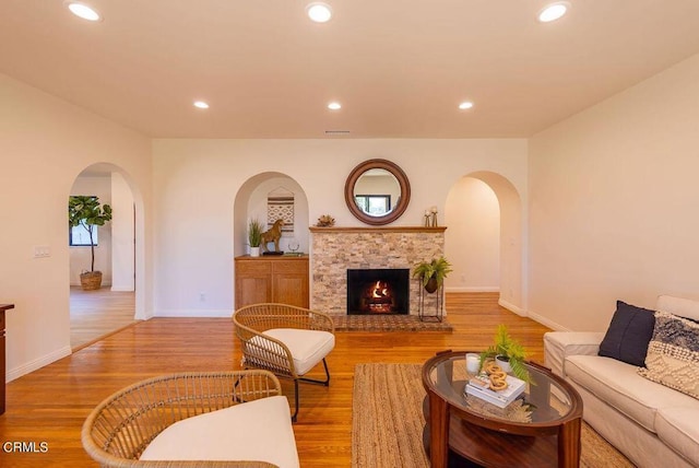 living room featuring a stone fireplace and light hardwood / wood-style floors