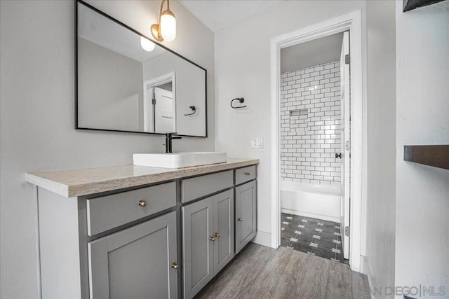 bathroom featuring wood-type flooring, vanity, and tiled shower / bath