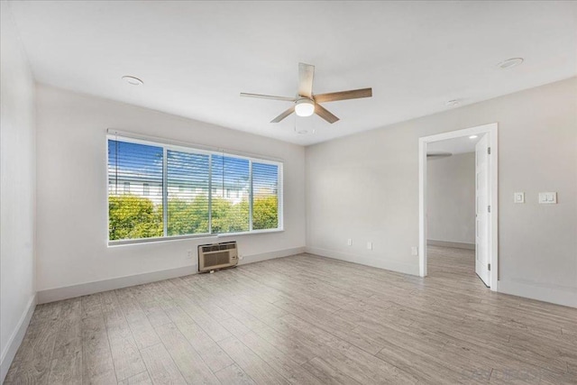 spare room with light hardwood / wood-style flooring, an AC wall unit, and ceiling fan