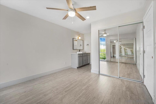 unfurnished bedroom featuring ceiling fan, sink, a closet, and light wood-type flooring