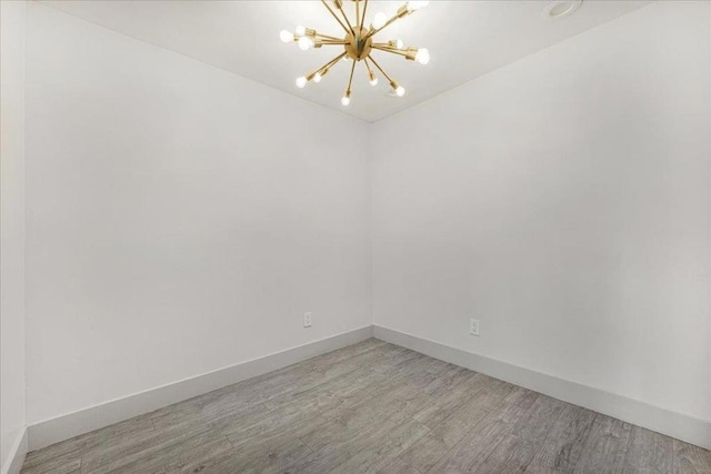 empty room featuring an inviting chandelier and hardwood / wood-style floors