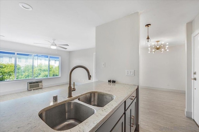 kitchen with sink, hanging light fixtures, a wall mounted AC, light stone countertops, and ceiling fan with notable chandelier