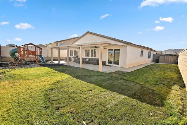 rear view of house featuring a playground, a fenced backyard, a yard, stucco siding, and a patio area