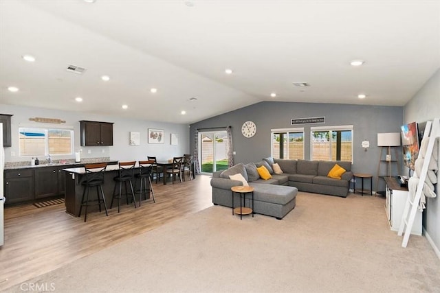 living area featuring a wealth of natural light, visible vents, vaulted ceiling, and recessed lighting