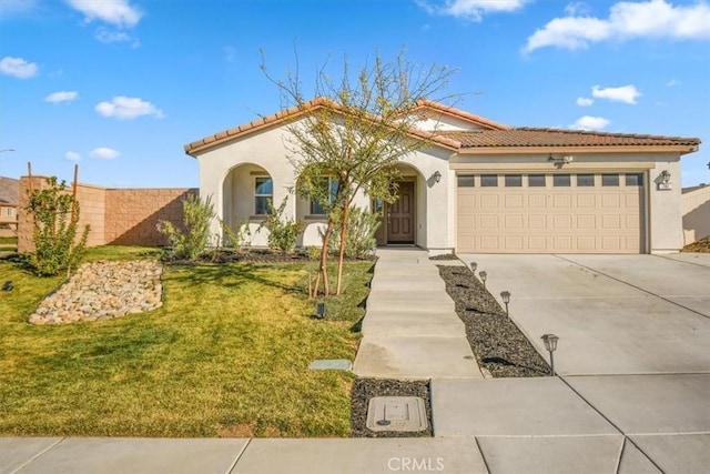 mediterranean / spanish-style home featuring stucco siding, concrete driveway, an attached garage, a front yard, and a tiled roof