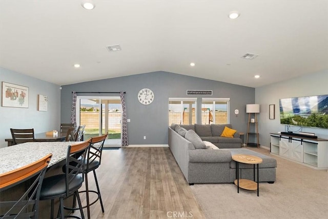 living area with lofted ceiling, light wood-type flooring, visible vents, and baseboards