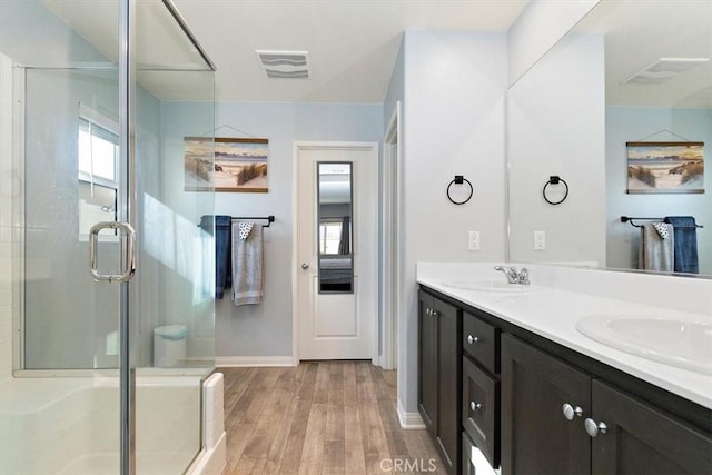 bathroom featuring a shower stall, visible vents, a sink, and wood finished floors