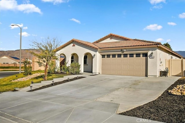 mediterranean / spanish-style home with a mountain view, a garage, a tile roof, driveway, and stucco siding