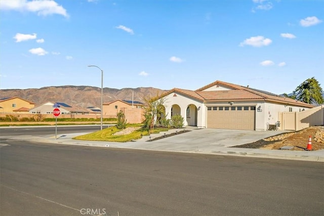 mediterranean / spanish home featuring an attached garage, a mountain view, a residential view, driveway, and a tiled roof