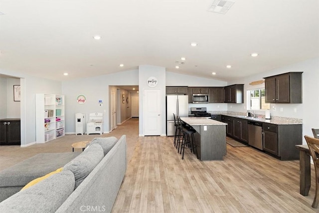 kitchen featuring stainless steel appliances, a center island, open floor plan, and light countertops