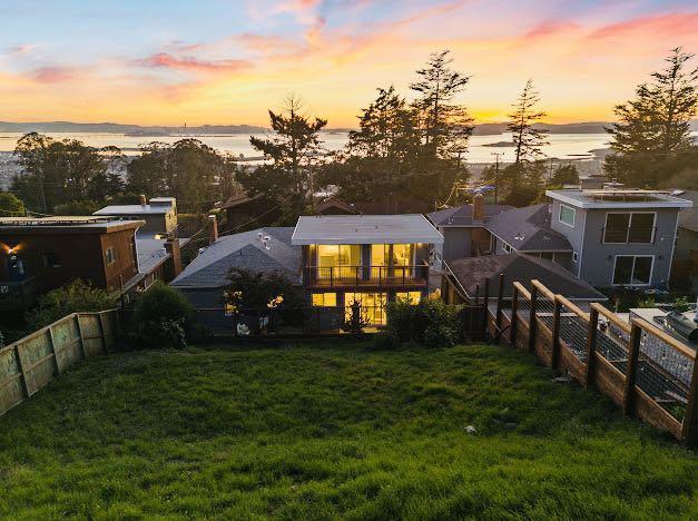 back house at dusk with a water view and a lawn