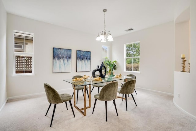 dining room with light colored carpet and a notable chandelier