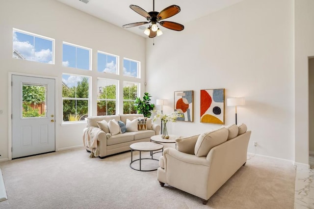 living room with ceiling fan, light colored carpet, and a towering ceiling